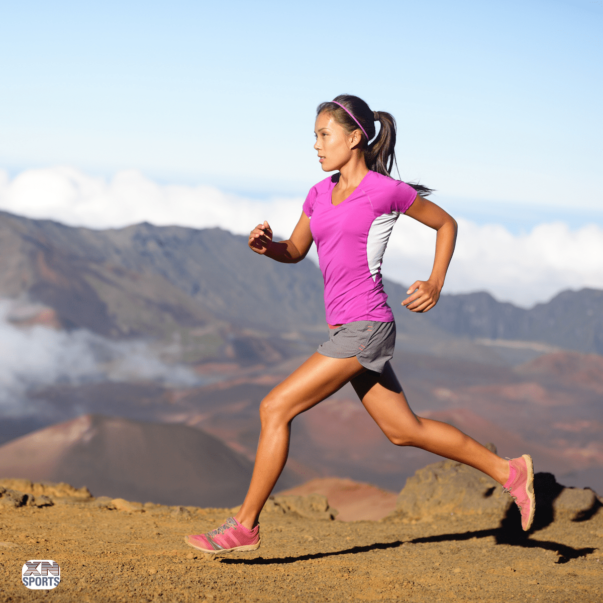 best headphones for running. Runner wearing a pink shirt, gray shorts, and pink sneakers.